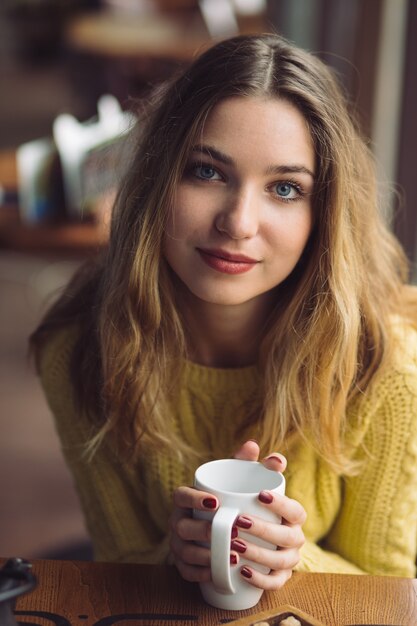 Trinkender Cappuccino des reizend Mädchens und essen Käsekuchen