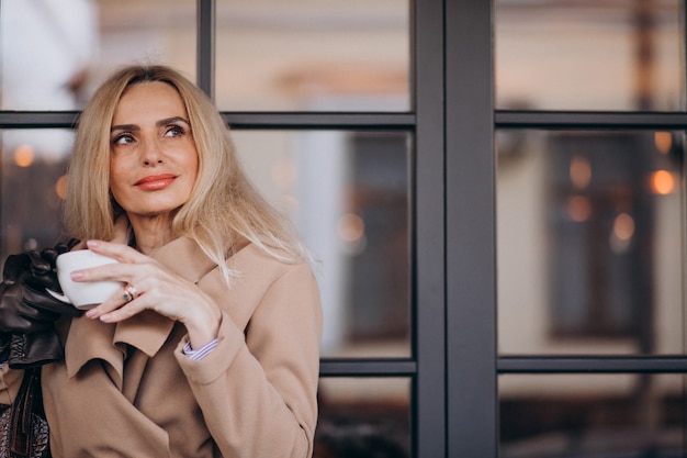 Trinkender Kaffee der älteren Frau außerhalb des Cafés