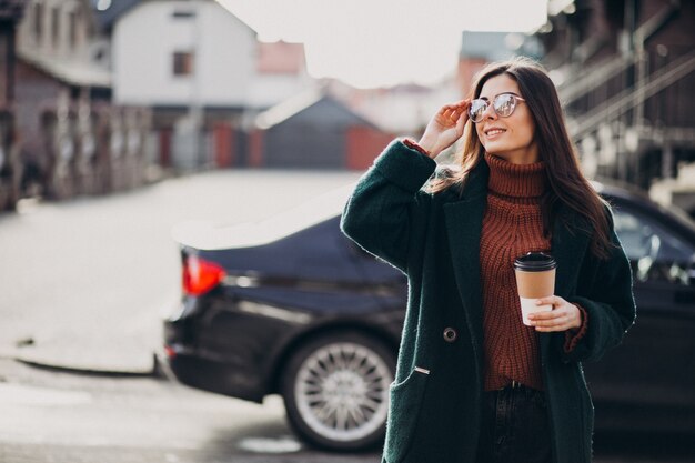 Trinkender Kaffee der jungen Frau durch ihr Auto