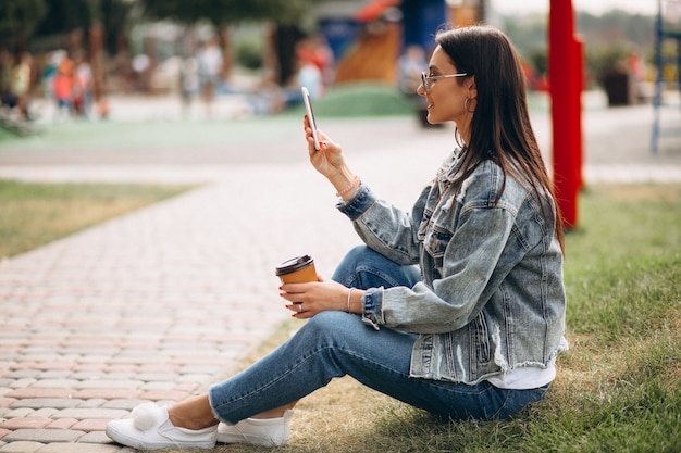 Trinkender Kaffee der jungen Frau im Park