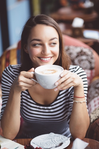 Kostenloses Foto trinkender kaffee der jungen frau im städtischen café