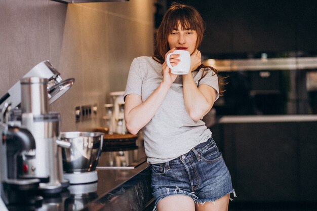 Trinkender Kaffee der jungen Frau morgens an der Küche