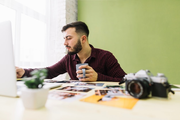 Kostenloses Foto trinkender kaffee des fotografen bei der arbeit