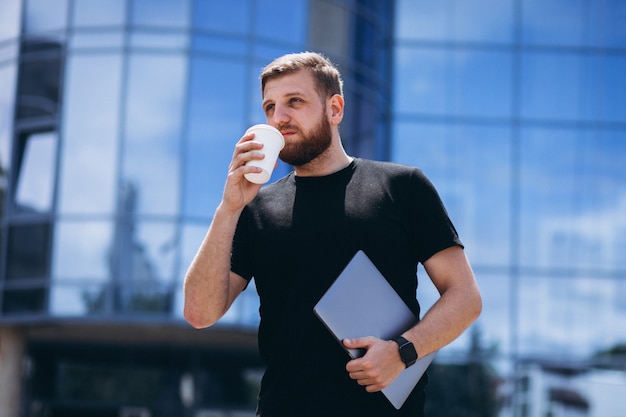 Trinkender Kaffee des jungen Geschäftsmannes mit Laptop