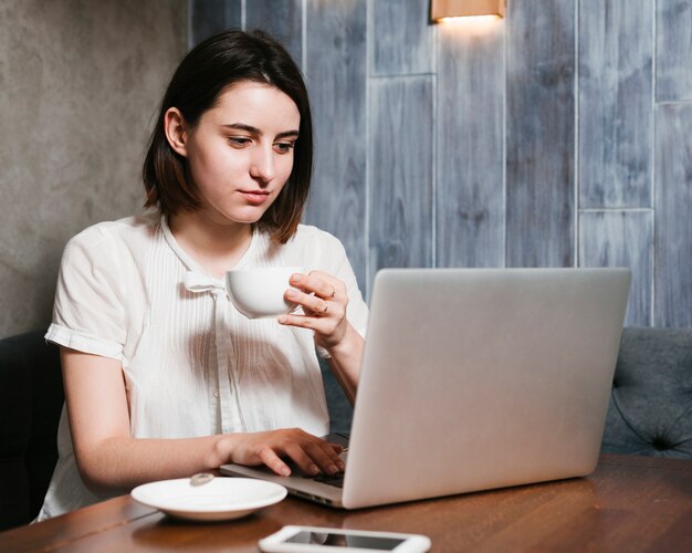 Kostenloses Foto trinkender kaffee des jungen mädchens am arbeitsplatz