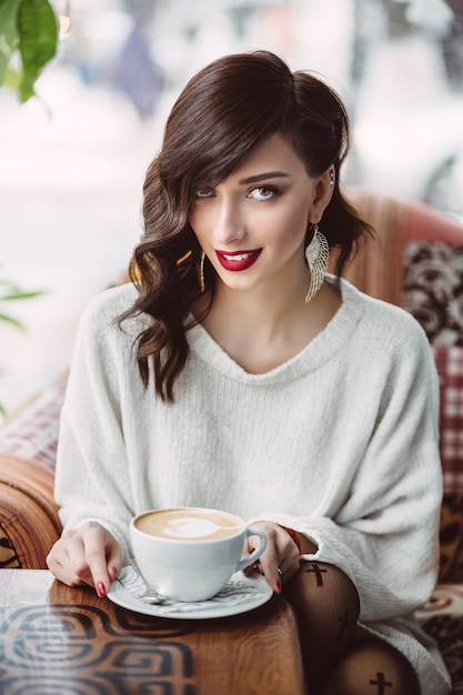 Trinkender Kaffee des jungen Mädchens in einem modischen Café