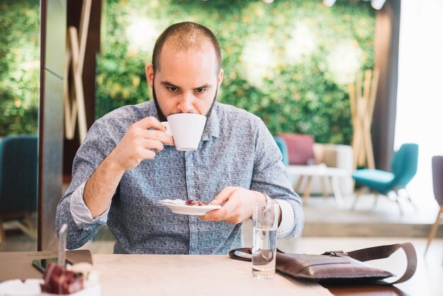 Trinkender Kaffee des unemotional Mannes in der Cafeteria