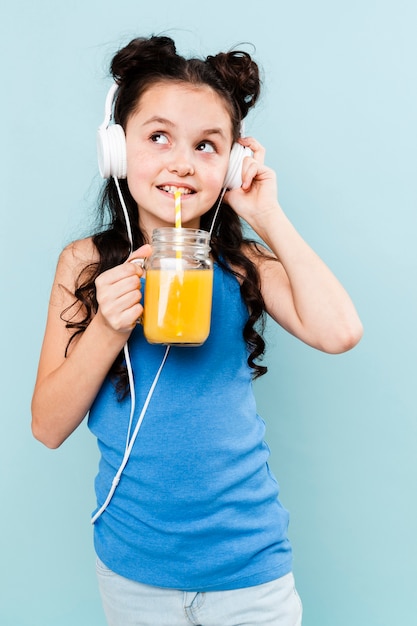 Trinkender Saft des Vorderansichtmädchens und hörende Musik