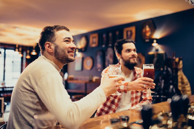 Trinkendes Bier des hübschen bärtigen Mannes zwei in der Kneipe