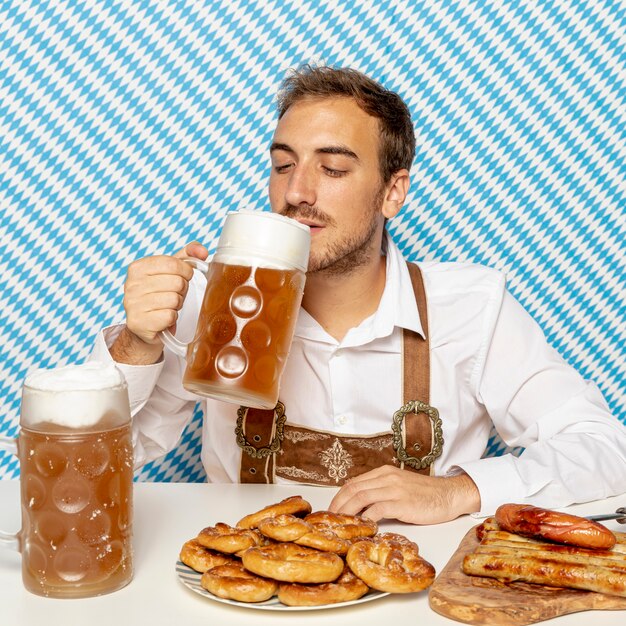 Trinkendes Bier des Mannes mit deutschem Lebensmittel