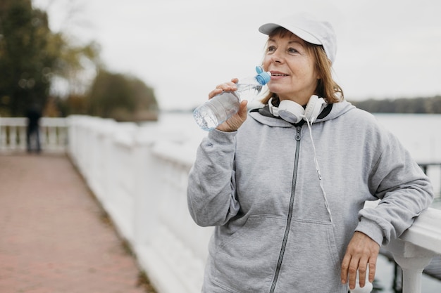 Trinkwasser der älteren Frau im Freien nach dem Training