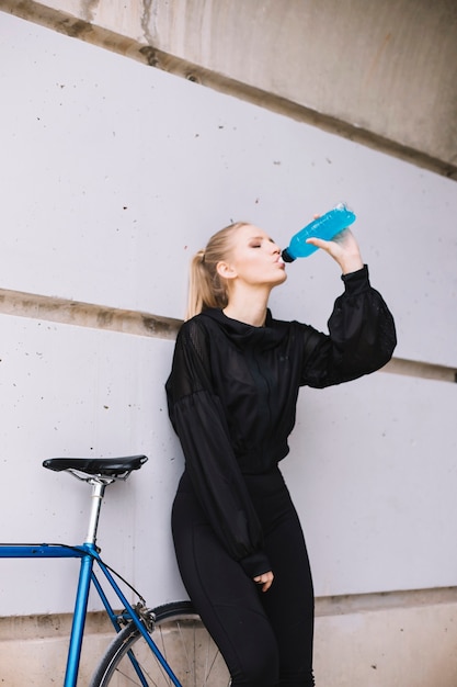 Kostenloses Foto trinkwasser der frau nahe fahrrad