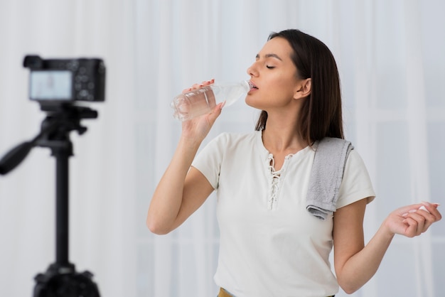 Trinkwasser der jungen Frau auf Kamera