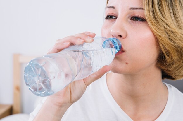 Trinkwasser der Nahaufnahmefrau von der Flasche