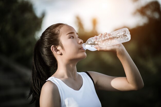 Trinkwasser der schönen jungen Eignungsfrau, nachdem Übung laufen gelassen worden ist