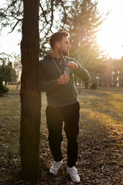 Trinkwasser des jungen Mannes draußen während des Trainings