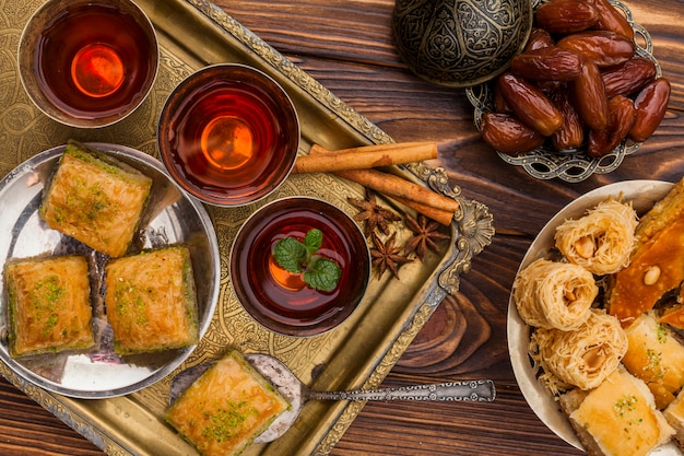 Trockene Datteln auf Untertasse in der Nähe von Tassen Tee und türkischen Desserts auf Tablett