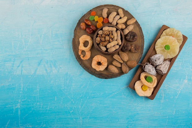 Trockene Früchte und Snacks in Holzplatten auf dem blauen Tisch