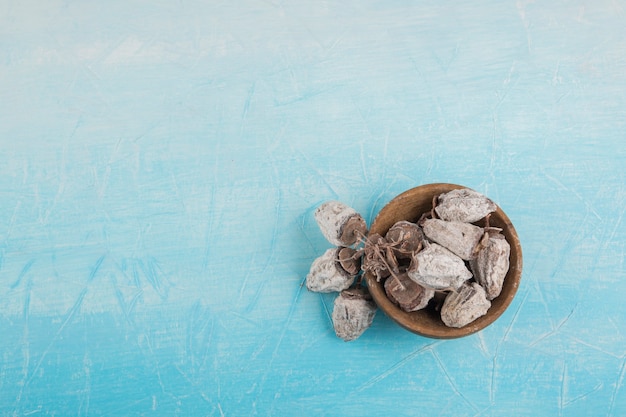 Trockene pflaume datiert in einer hölzernen untertasse auf blauem raum