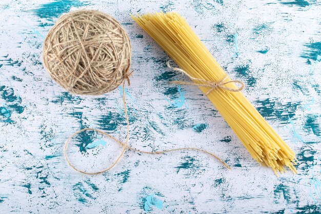 Kostenloses Foto trockene spaghetti-nudeln und garn auf blau.