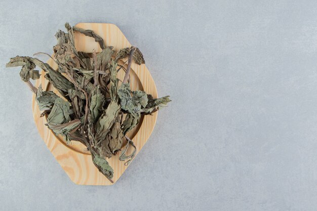 Trockene Teeblätter auf Holzplatte.