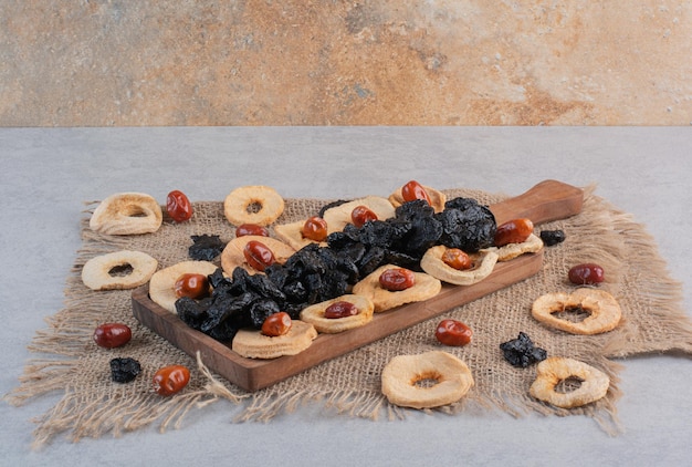 Kostenloses Foto trockenfrüchte wie apfelscheiben, schwarze sultaninen und jujube-beeren auf betonoberfläche.