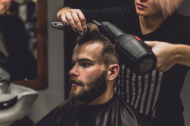 Trocknendes Haar der Herrenfriseurfrau des Kunden