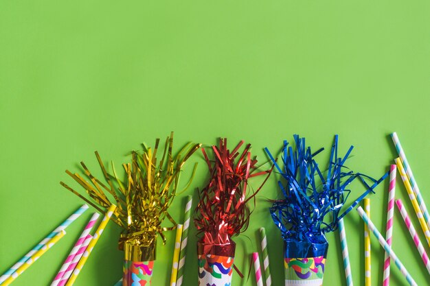 Trompeten mit Serpentin und bunten Sticks auf einem grünen Tisch