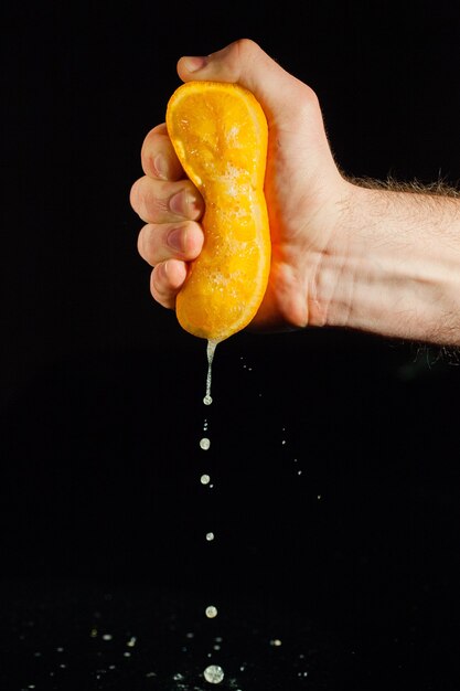 Tropfen Saft fallen von einer Orange in die Hand des Mannes