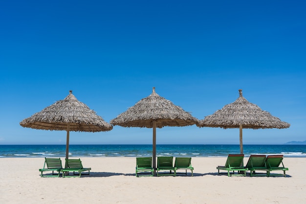 Tropischer sandstrand und sommermeerwasser mit blauem himmel und regenschirm mit drei strohhalmen in der stadt danang, vietnam. reise- und naturkonzept
