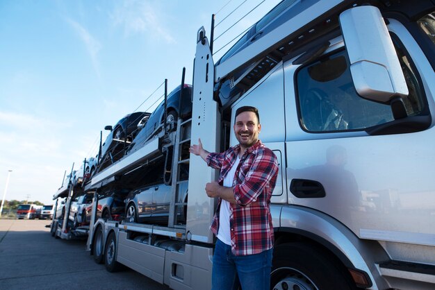 Trucker mittleren Alters vor dem LKW-Anhänger mit Autos