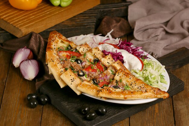 Türkische Pide mit Oliven und Tomaten auf einem Holzbrett