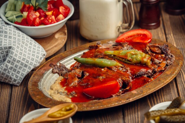 Türkisches iskender doner in der kupfernen Platte mit Tomatensauce und grünem Pfeffer.