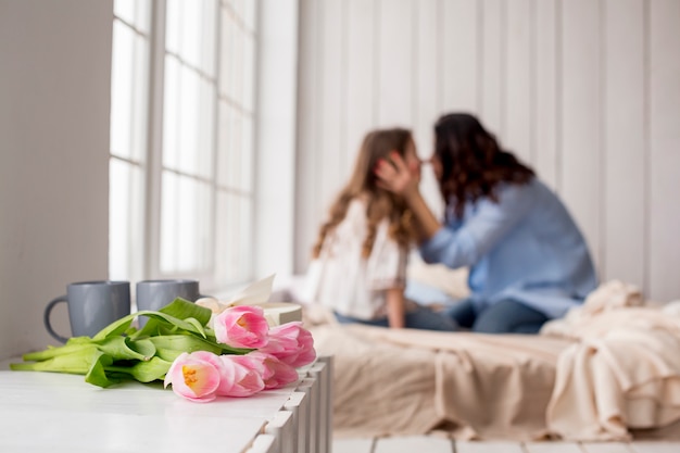 Tulpe blüht auf Tabelle nahe Bett mit dem Umarmen der Mutter und der Tochter