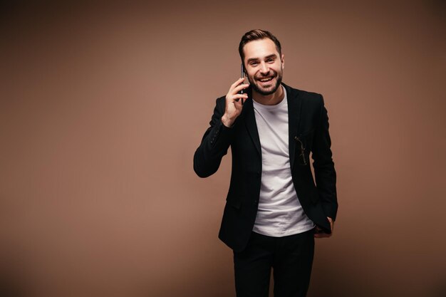 Typ in Anzug und weißem T-Shirt telefoniert und schaut in die Kamera