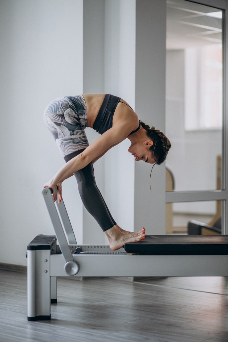 Kostenlose Foto übendes pilates der frau in einem pilates reformer