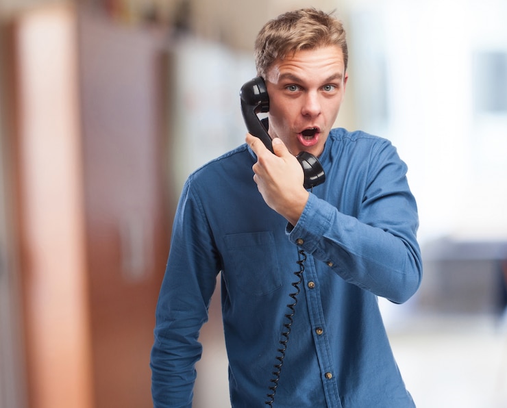 Kostenlose Foto überrascht mann auf einem antiken telefon sprechen