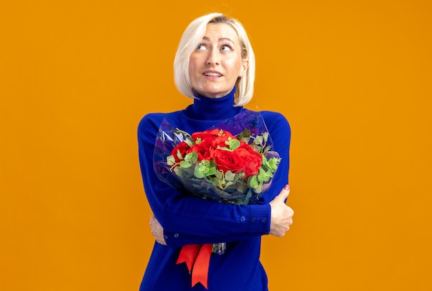 Überraschte hübsche slawische frau mit blumenstrauß und blick auf die seite am valentinstag