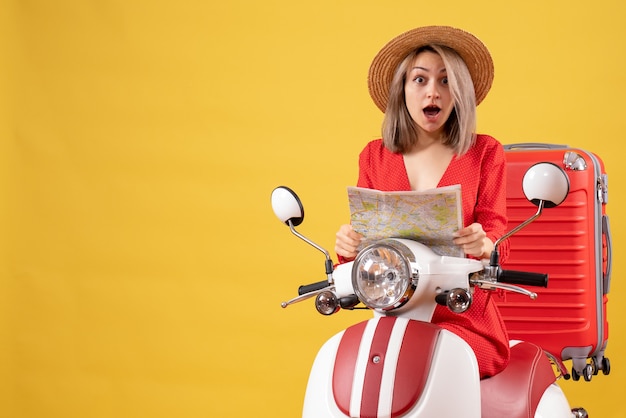 überraschte junge Dame auf Moped mit rotem Koffer mit Karte