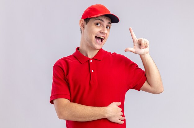 Überraschter junger kaukasischer lieferbote im roten hemd, das nach oben zeigt