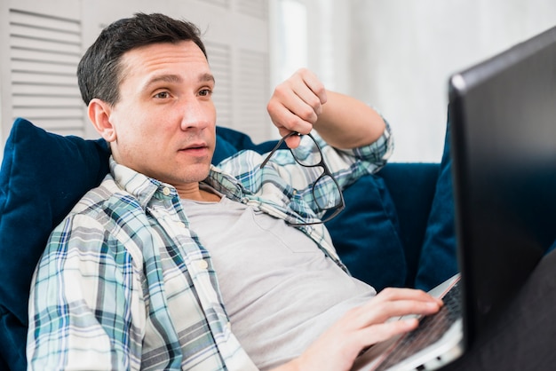 Kostenloses Foto Überraschter mann, der laptop auf sofa verwendet