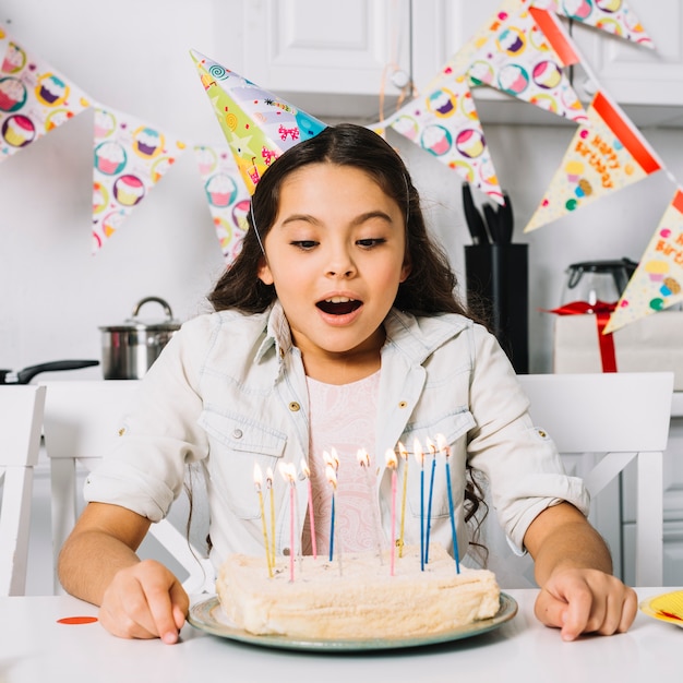 Überraschter schlagkuchen des geburtstagsmädchens mit belichteten kerzen