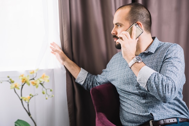 Kostenloses Foto Überzeugter mann, der zu hause am telefon spricht