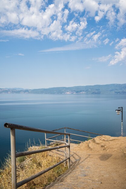 Ufer mit metallischen Zäunen, umgeben vom Meer mit Bergen im Hintergrund