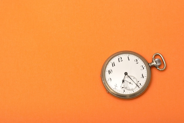 Uhr auf einer orangefarbenen Oberfläche - Zeitmanagementkonzept