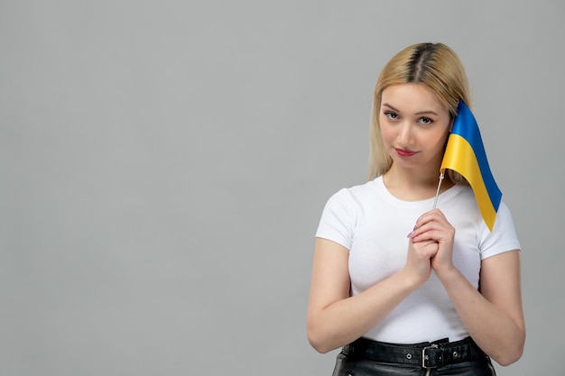 ukraine russisch konflikt blondes süßes mädchen mit rotem lippenstift, der die ukrainische flagge an den kopf hält