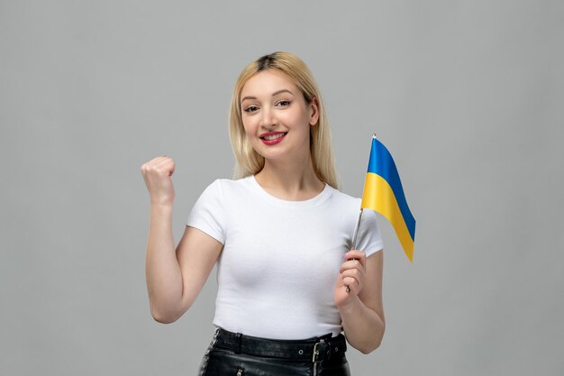 Ukraine russischer Konflikt blondes süßes Mädchen mit rotem Lippenstift und ukrainischer Flagge, die die Faust hochhält