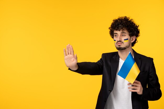 Ukraine-Russland-Konflikt junger Mann im schwarzen Blazer mit ukrainischer Flagge im Gesicht mit Flagge