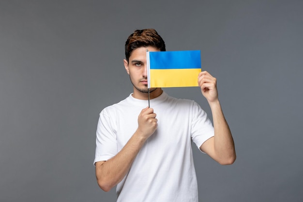 Ukraine-Russland-Konflikt mutiger gutaussehender Kerl im weißen Hemd mit bedeckendem Gesicht mit Flagge