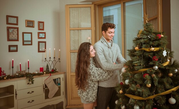 Umarmende Paare bei der Verzierung nach Hause für Weihnachten
